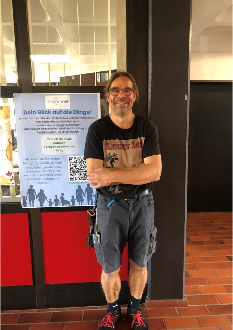 Kollege, Nachbar und Hausmeister zugleich: Stefan, stehend im Eingang des Rathauses vor unserem Plakat der "Aktivierenden Befragung", die wir aktuell durchführen.