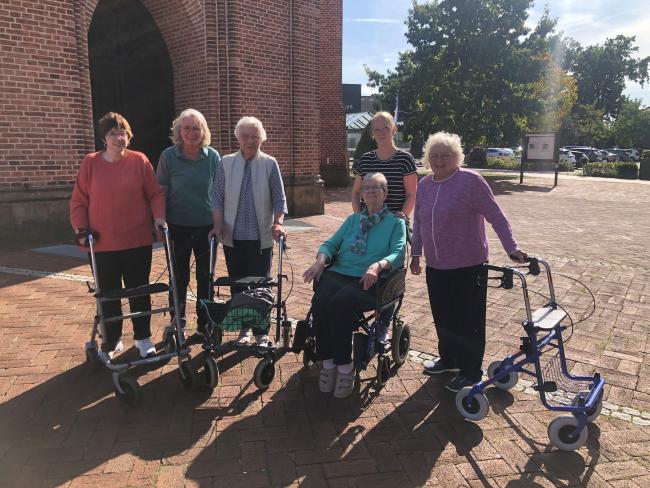 Drei Besucherinnen der Tagespflege von nebenan, mit zwei ihrer Betreuerinnen, auf dem Kirchvorplatz.
