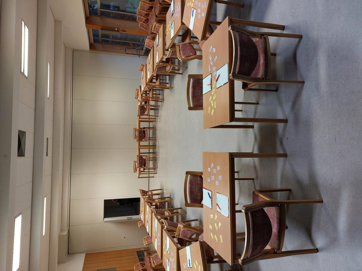 30 Tische in einem Oval, bestückt mit Klemmbrettern und Stiften. Innen und außen Stühle.